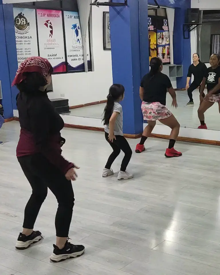 Clase de Baile: mujeres y niñas siguen la coreografía frente al espejo.