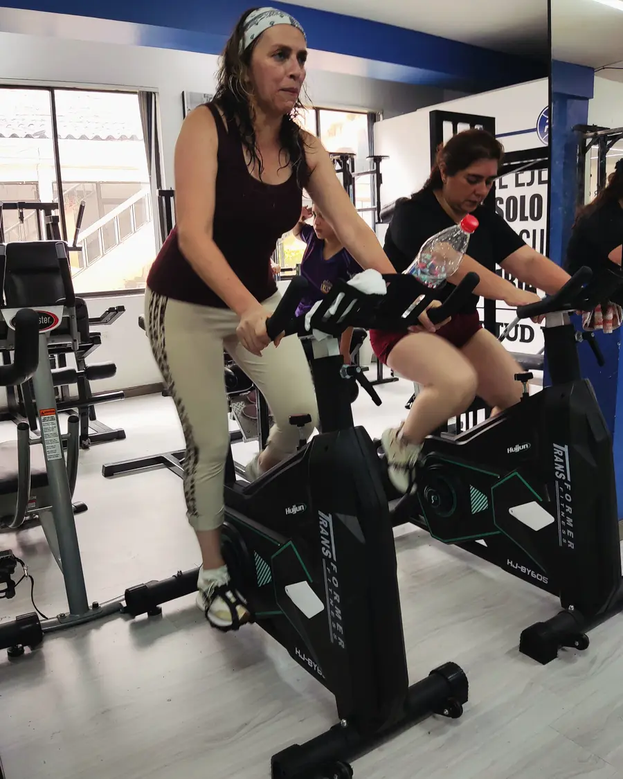 Dos socias pedalean en las bicicletas estáticas de la zona de cardio.